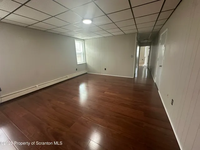 an empty room with wooden floor cabinet and windows