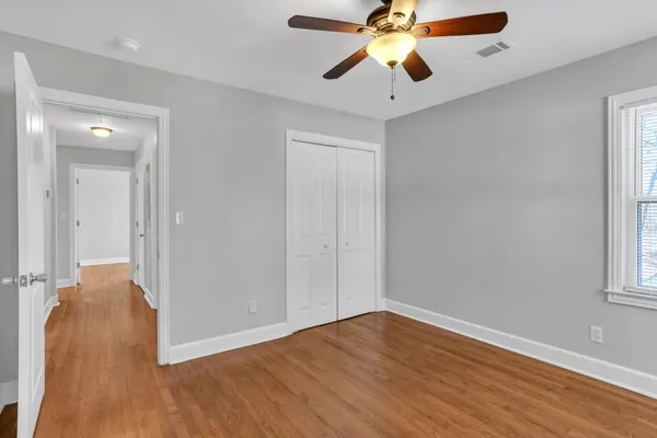 a view of an empty room with wooden floor and a window