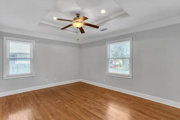 an empty room with wooden floor and a ceiling fan