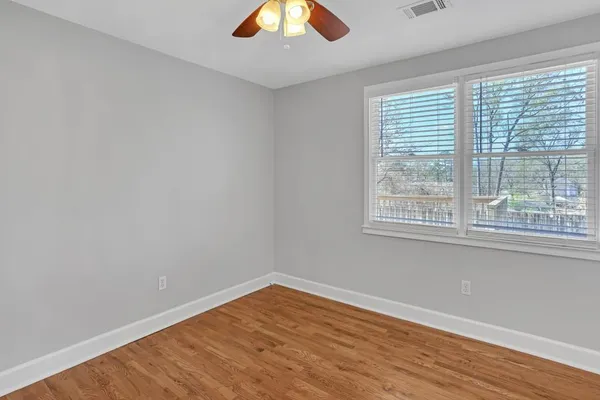 an empty room with wooden floor and windows