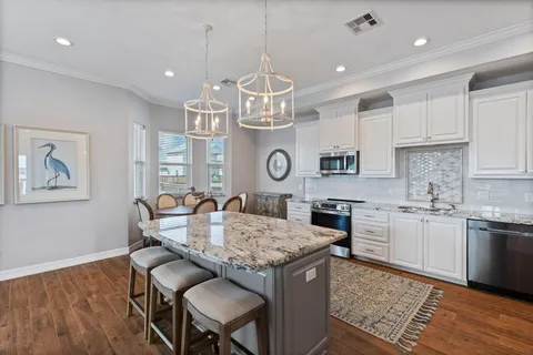 a kitchen with granite countertop kitchen island stainless steel appliances a dining table and chairs in it