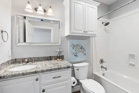 a bathroom with a granite countertop sink toilet and shower
