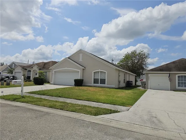 a view of a white house next to a yard with big trees