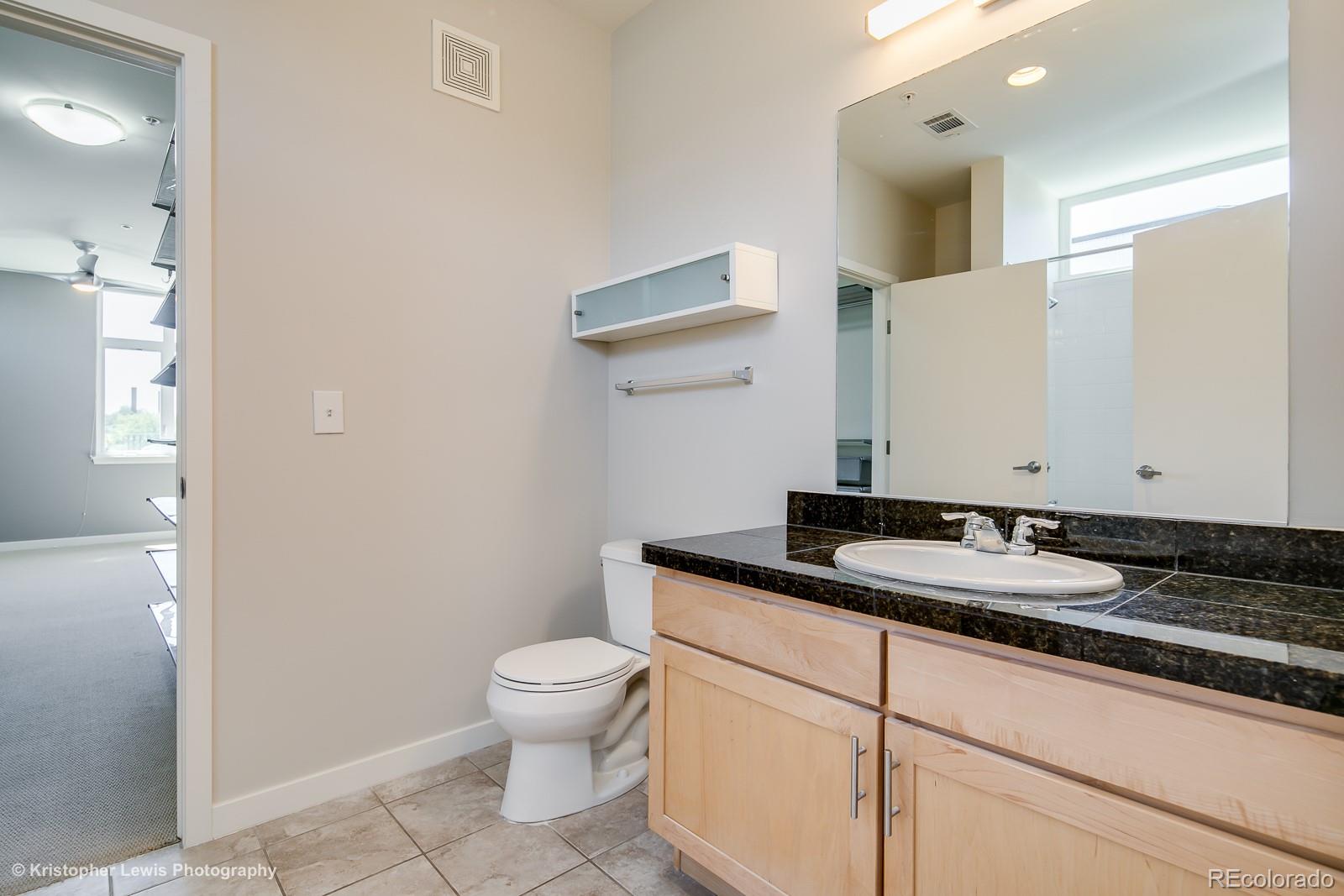3101 Blake Street, Unit 308 Denver, CO 80205 - Photo 15 of 19 a bathroom with a granite countertop sink a toilet and a mirror