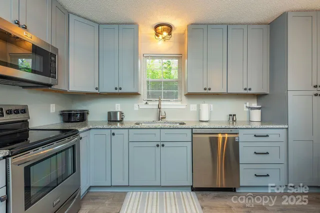 a kitchen with stainless steel appliances granite countertop a stove a sink and a microwave