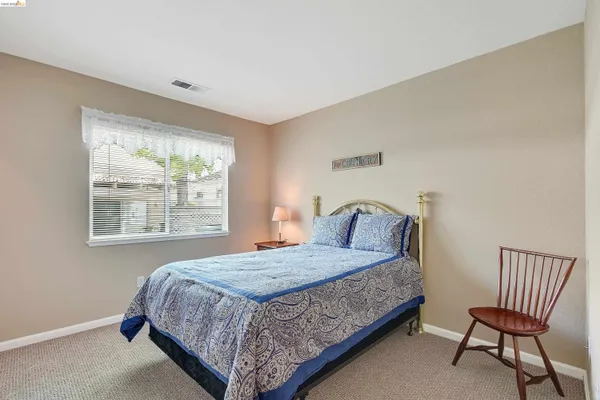a bedroom with a bed chair and two windows