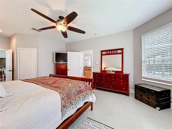 a spacious bedroom with a bed a dresser and potted plant