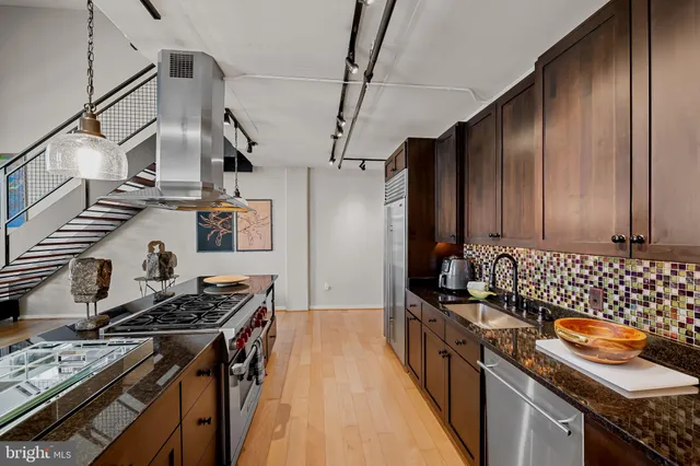 a kitchen with granite countertop a stove a sink and a refrigerator