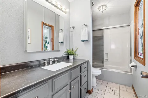 a bathroom with a granite countertop sink a toilet a mirror and shower