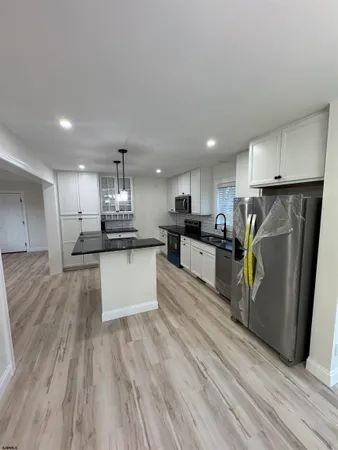 a kitchen with stainless steel appliances kitchen island granite countertop a refrigerator and a stove top oven