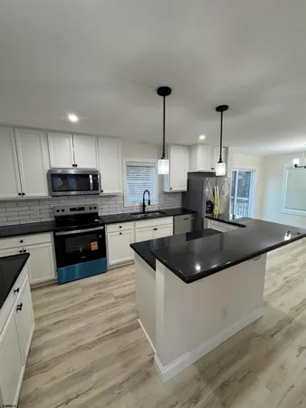 a kitchen with stainless steel appliances granite countertop a sink a stove and a wooden floors
