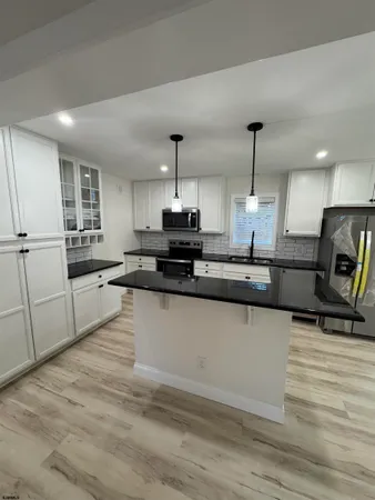 a large kitchen with granite countertop a sink a counter space appliances and cabinets