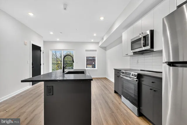 a kitchen with stainless steel appliances granite countertop a stove a sink and a refrigerator