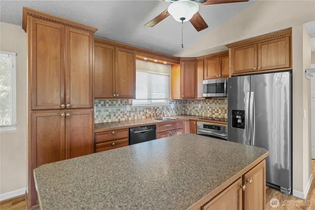 a kitchen with stainless steel appliances granite countertop a refrigerator a sink dishwasher a stove with wooden cabinets and floor