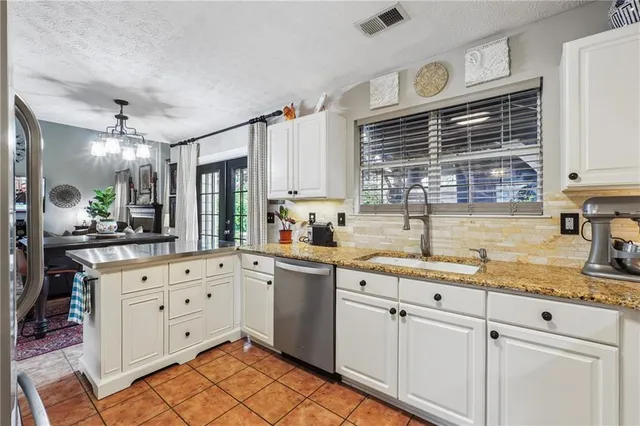 a kitchen with granite countertop a sink cabinets window and stainless steel appliances