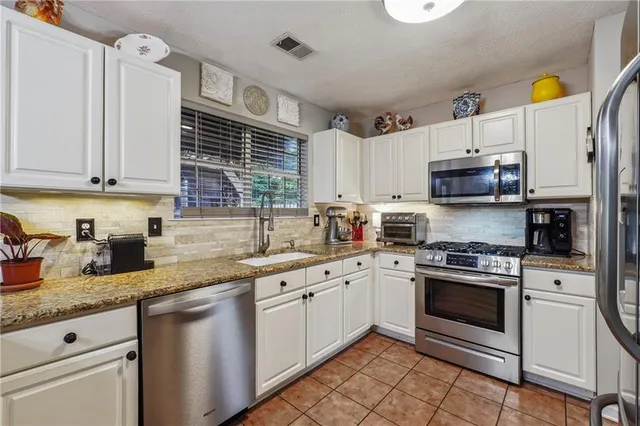 a kitchen with granite countertop a sink stainless steel appliances and cabinets