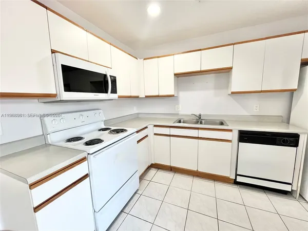 a white kitchen with stainless steel appliances granite countertop a sink and a stove