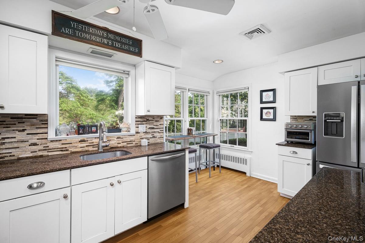 4 Wagon Wheel Road Mamaroneck, NY 10543 - Photo 11 of 31 Kitchen featuring dark stone countertops, appliances with stainless steel finishes, white cabinetry, decorative backsplash, and recessed lighting