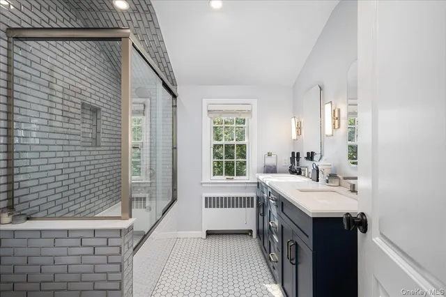 a bathroom with a double vanity sink a large mirror and shower