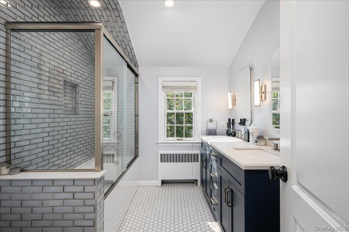 4 Wagon Wheel Road Mamaroneck, NY 10543 - Photo 15 of 31 Full bath featuring radiator heating unit, double vanity, a tile shower, vaulted ceiling, and recessed lighting