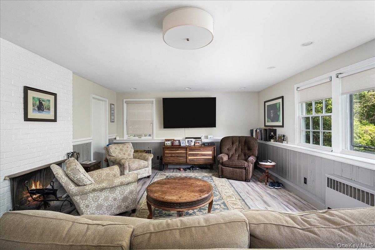 4 Wagon Wheel Road Mamaroneck, NY 10543 - Photo 20 of 31 Living room with radiator, wainscoting, a brick fireplace, and wood finished floors