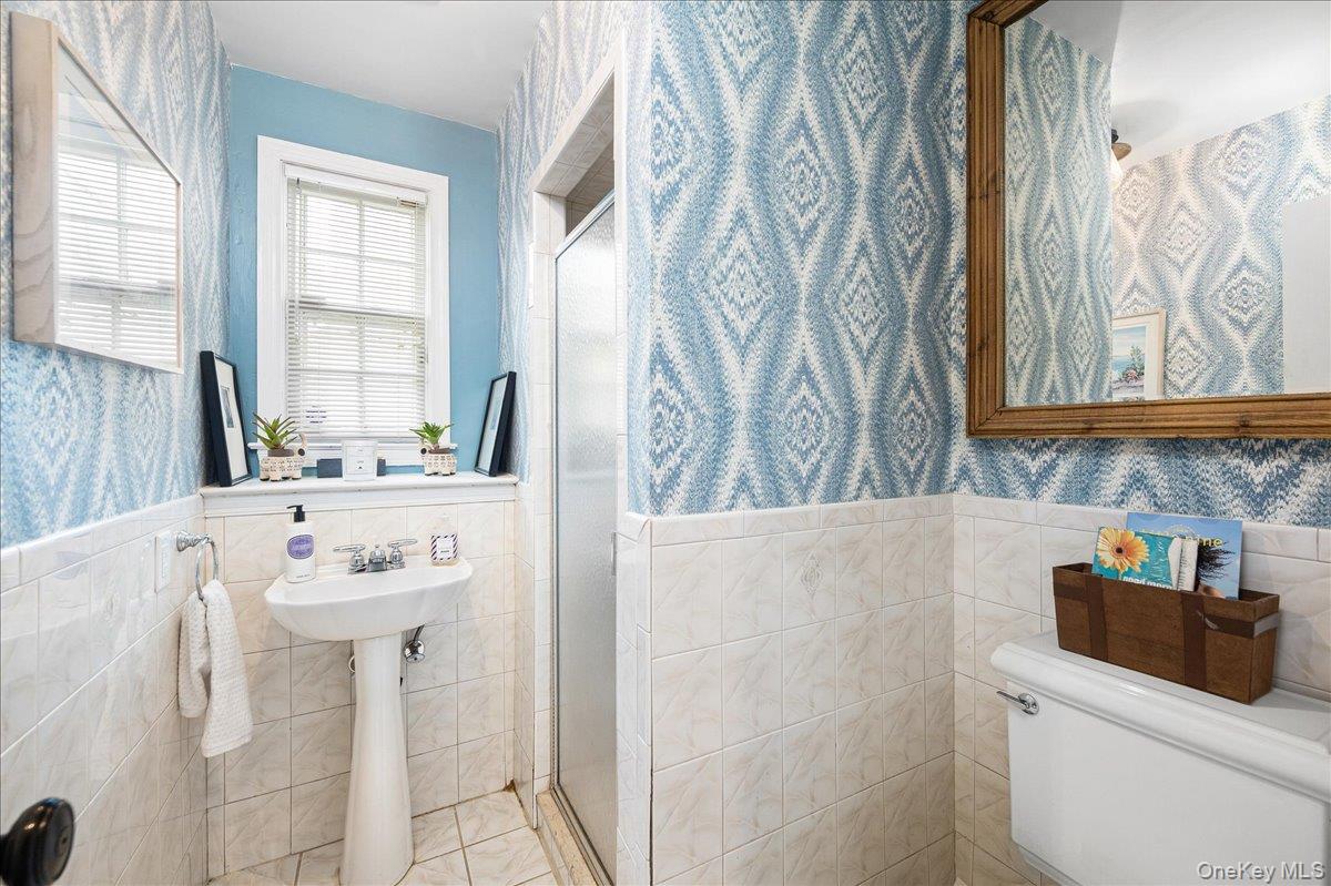 4 Wagon Wheel Road Mamaroneck, NY 10543 - Photo 23 of 31 Bathroom with wallpapered walls, a wainscoted wall, tile walls, and a shower stall