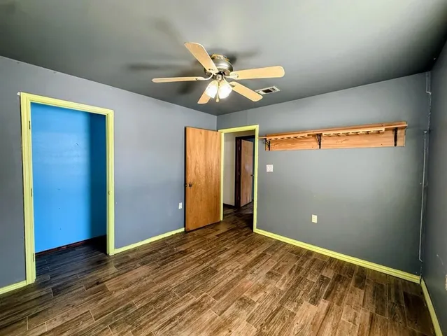 a view of a room with a ceiling fan and wooden floor