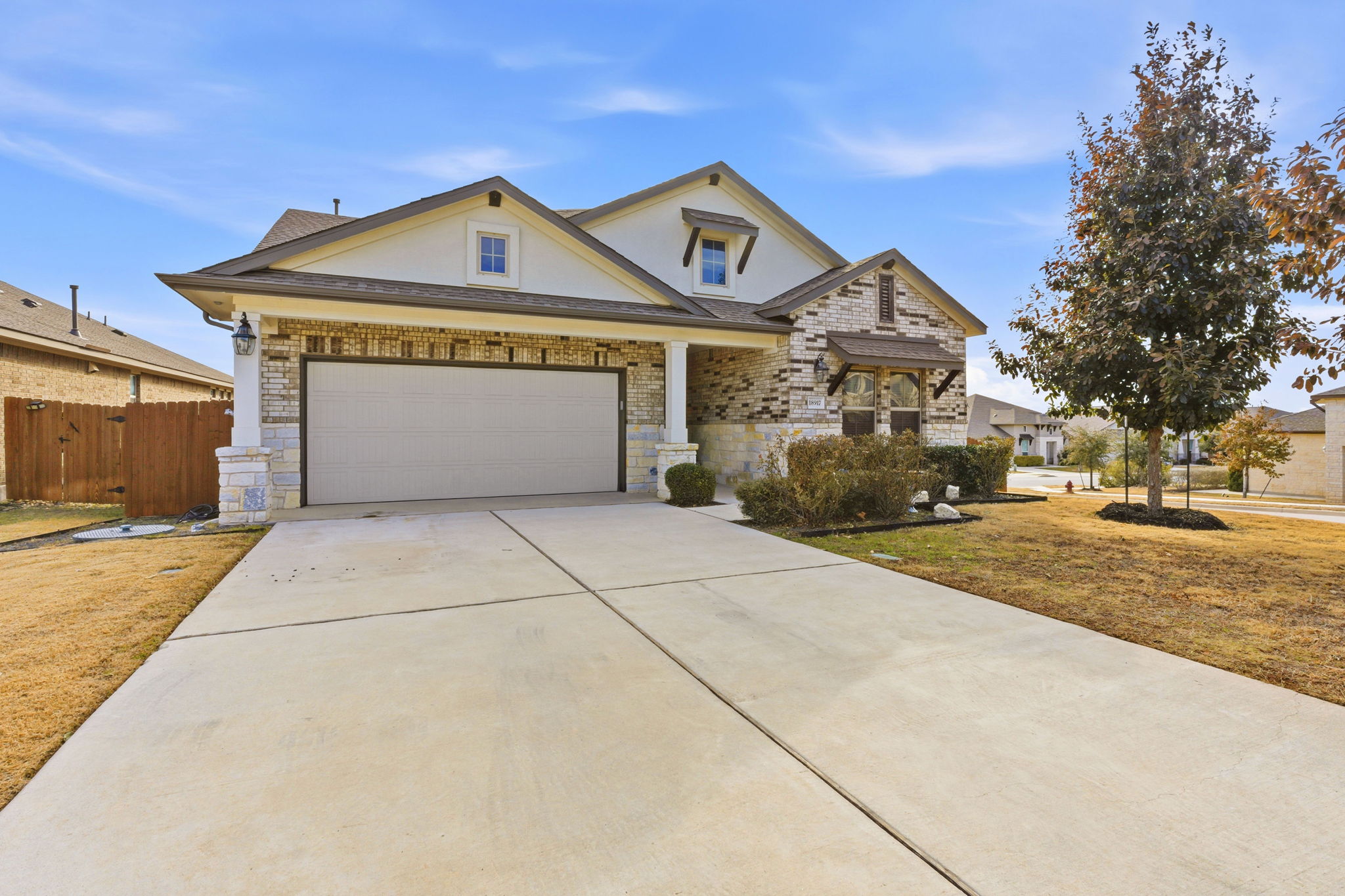 18917 Grape Seed Cove Austin, TX 78738 - Photo 1 of 33 View of front facade featuring concrete driveway, stucco siding, brick siding, an attached garage, and stone siding