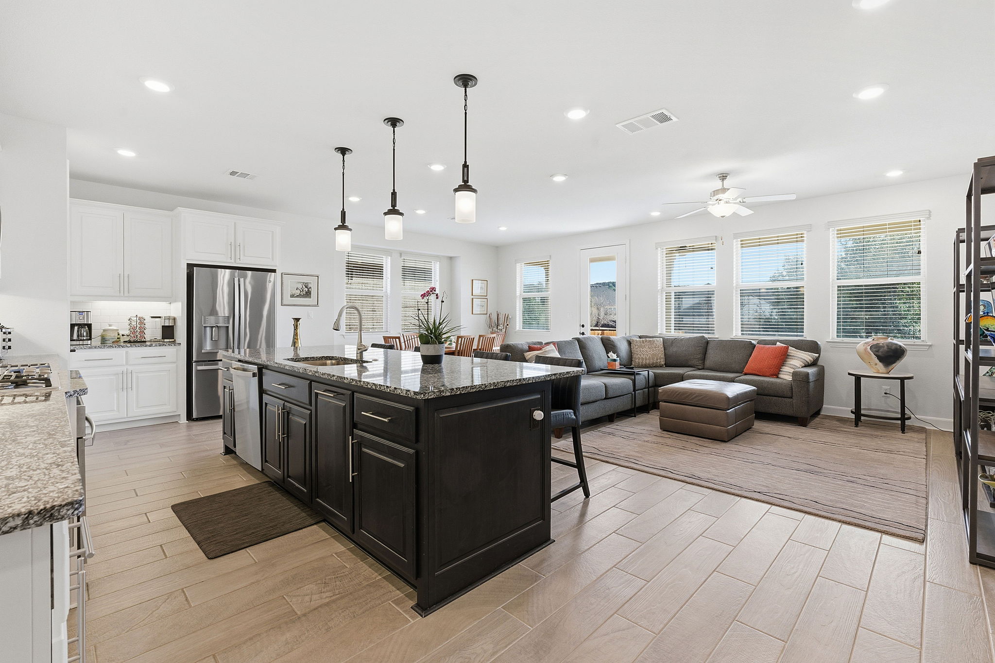 18917 Grape Seed Cove Austin, TX 78738 - Photo 2 of 33 Two tone kitchen with a breakfast bar, pendant lighting, wood tiled floors, stainless steel appliances, and dark stone countertops