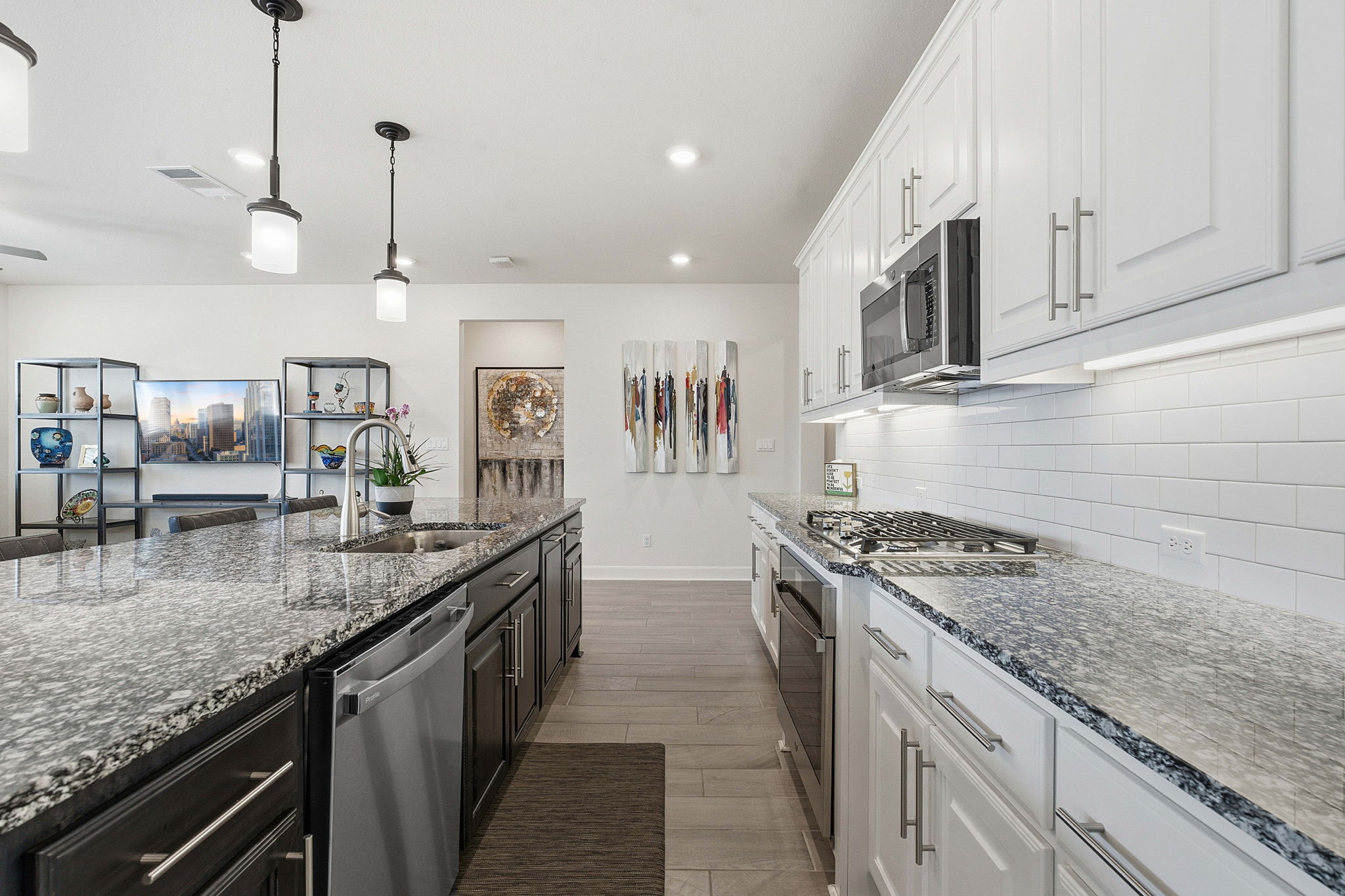 18917 Grape Seed Cove Austin, TX 78738 - Photo 21 of 33 Kitchen featuring two tone cabinetry, decorative light fixtures, dark stone countertops, stainless steel appliances, and light wood-type flooring