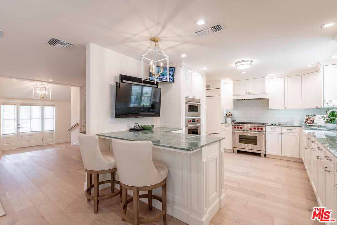 10821 Savona Road Los Angeles, CA 90077 - Photo 8 of 26 a open kitchen with stainless steel appliances kitchen island granite countertop a stove top oven a sink a dining table and chairs
