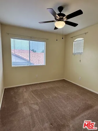 an empty room with a ceiling fan and window