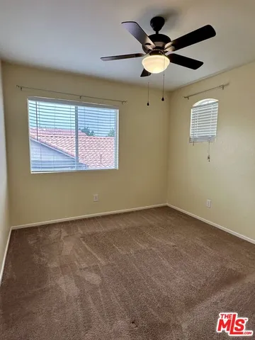 an empty room with a ceiling fan and window