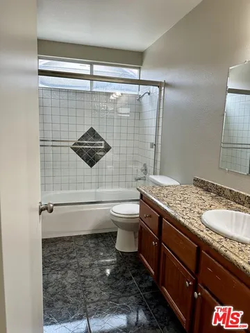 a bathroom with a granite countertop sink toilet and shower