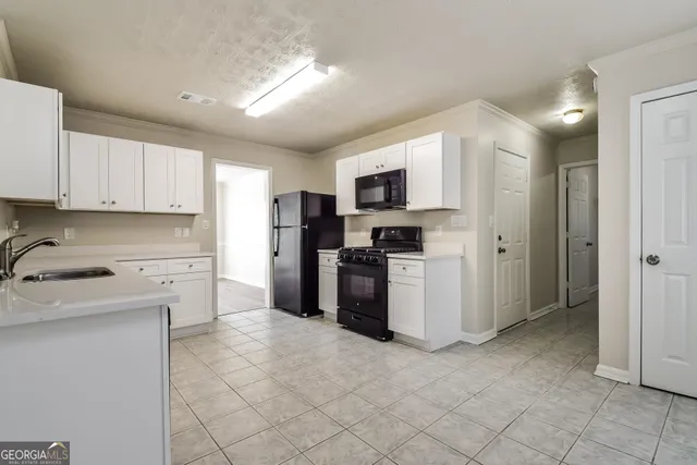 a kitchen with a refrigerator a stove top oven a sink and cabinets