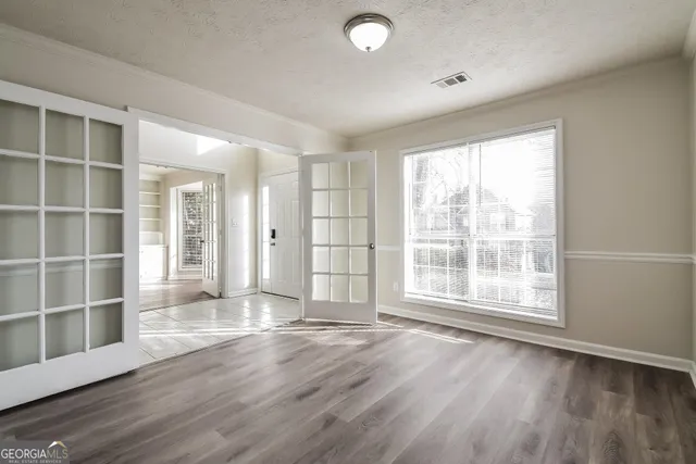 an empty room with wooden floor and windows