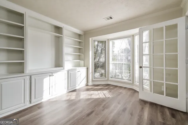 a view of an empty room with a window and wooden floor