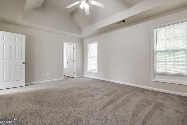 an empty room with a chandelier fan and windows