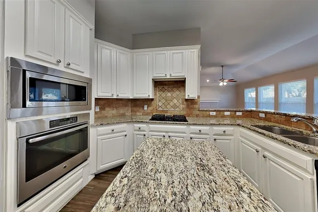 a kitchen with granite countertop a stove top oven microwave and cabinets