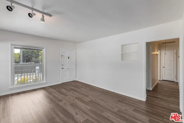 a view of an empty room with wooden floor and a window
