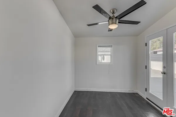 an empty room with wooden floor and ceiling fan