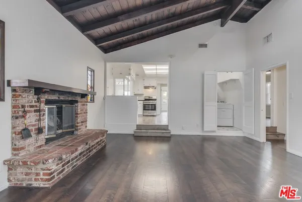 a view of a livingroom with wooden floor and a kitchen