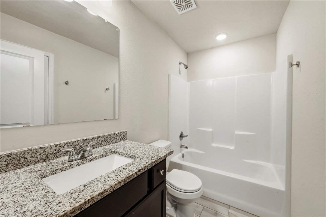 303 Camp Bowie Road Caldwell, TX 77836 - Photo 24 of 25 a bathroom with a granite countertop sink a toilet and bathtub