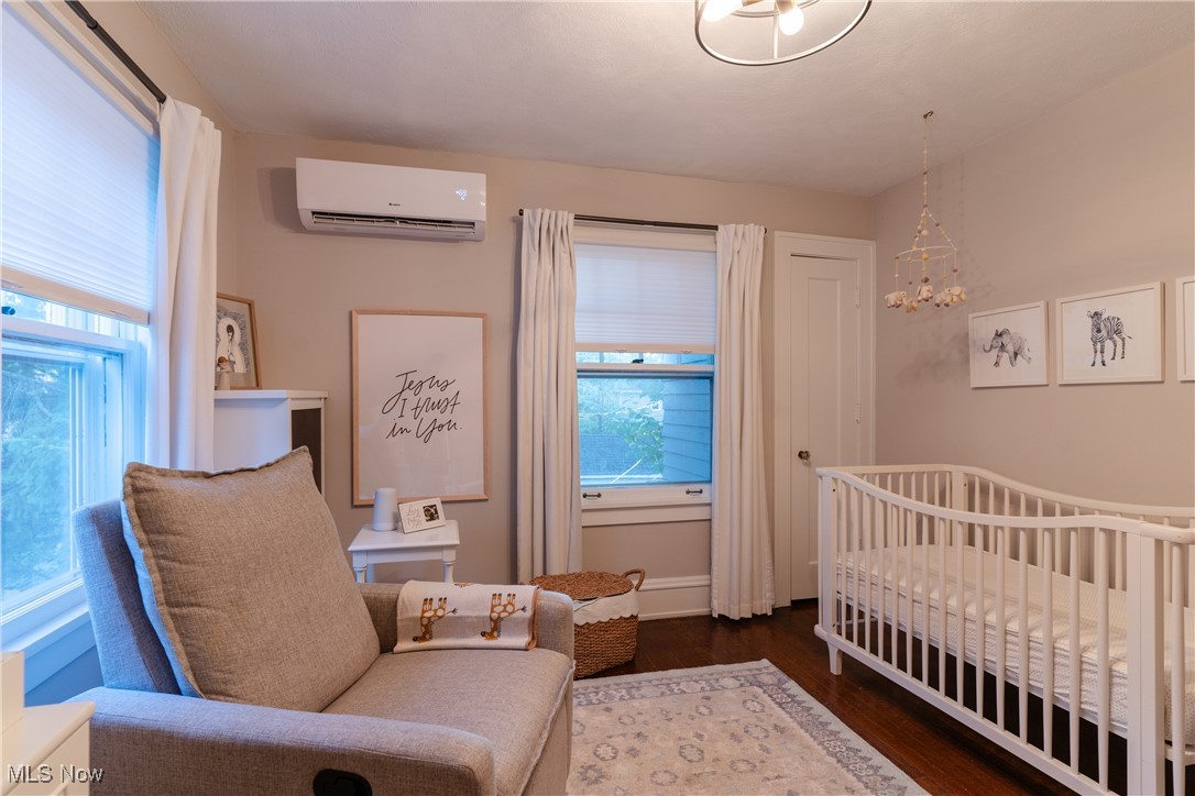 2890 Huntington Road Cleveland, OH 44120 - Photo 28 of 41 Bedroom with a nursery area, a notable chandelier, dark wood-type flooring, and a wall mounted air conditioner