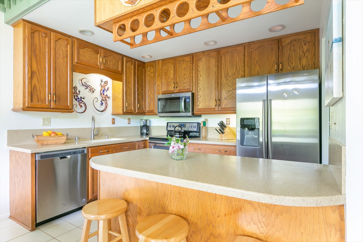 3880 Wyllie Road, Unit 8C Princeville, HI 96722 - Photo 6 of 17 a kitchen with stainless steel appliances granite countertop a sink refrigerator and cabinets