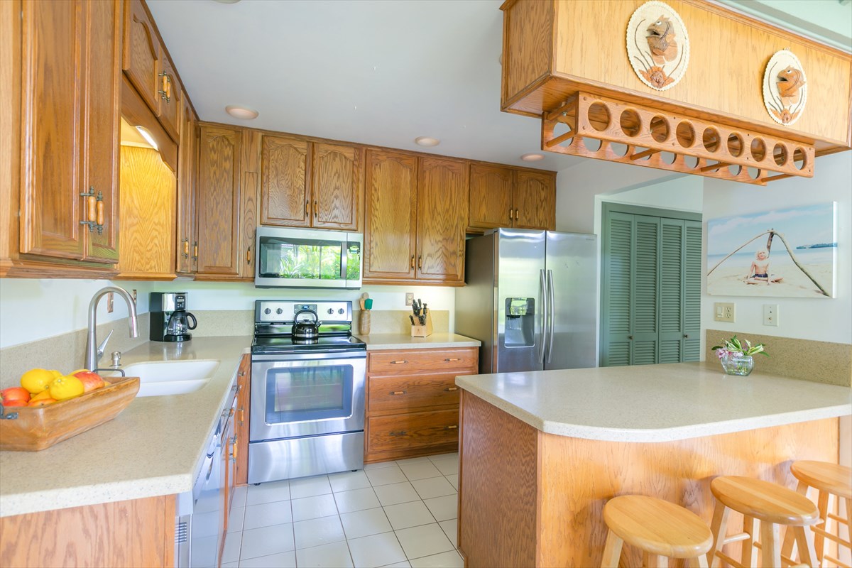 3880 Wyllie Road, Unit 8C Princeville, HI 96722 - Photo 8 of 17 a kitchen with stainless steel appliances granite countertop a sink a stove and a refrigerator