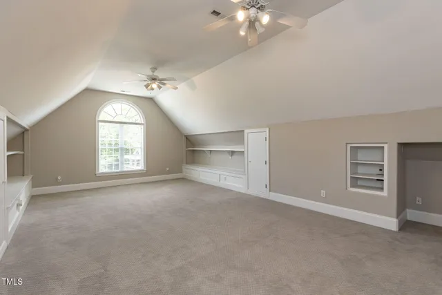 an empty room with windows and chandelier fan