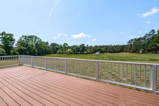 a view of deck with lots of green space and wooden fence