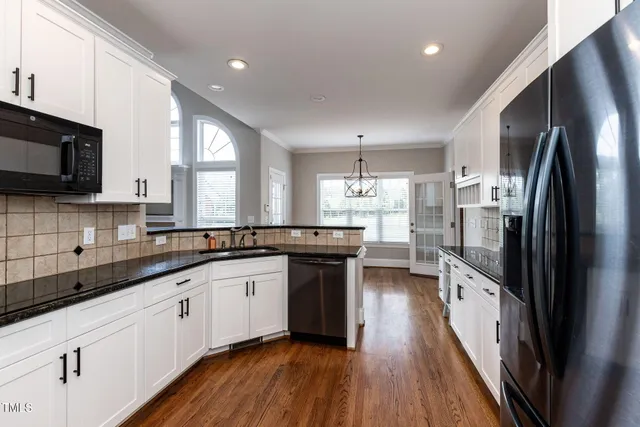 a kitchen with stainless steel appliances a sink dishwasher a refrigerator a stove top oven a sink and dishwasher with wooden floor