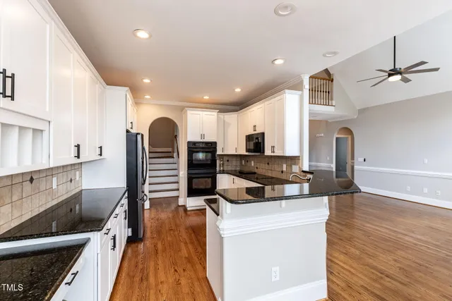 a kitchen with stainless steel appliances granite countertop a sink a stove and a wooden floors